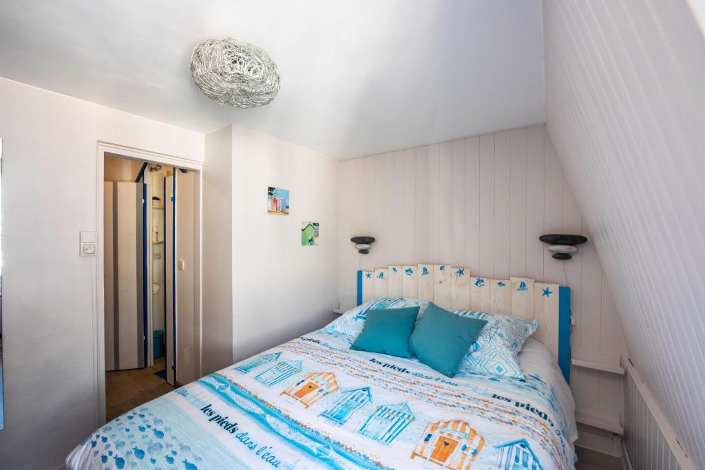 a bedroom with a bed with blue pillows at Maison de pêcheur LE TREPORT "ça nous va" in Le Tréport