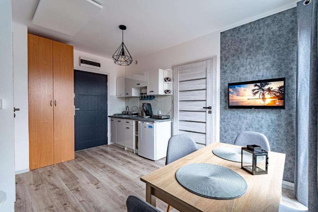 a kitchen and a dining room with a table and chairs at Apartament Kapitańska in Niechorze