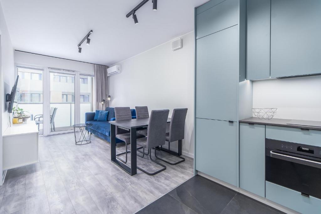 een keuken en eetkamer met een tafel en een blauwe bank bij Blue Sea Apartamenty Kasprowicza in Kołobrzeg