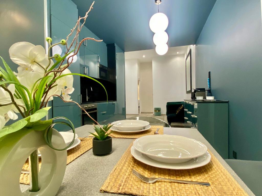 une table avec deux assiettes et un vase avec des fleurs dans l'établissement Appartement République, à Paris