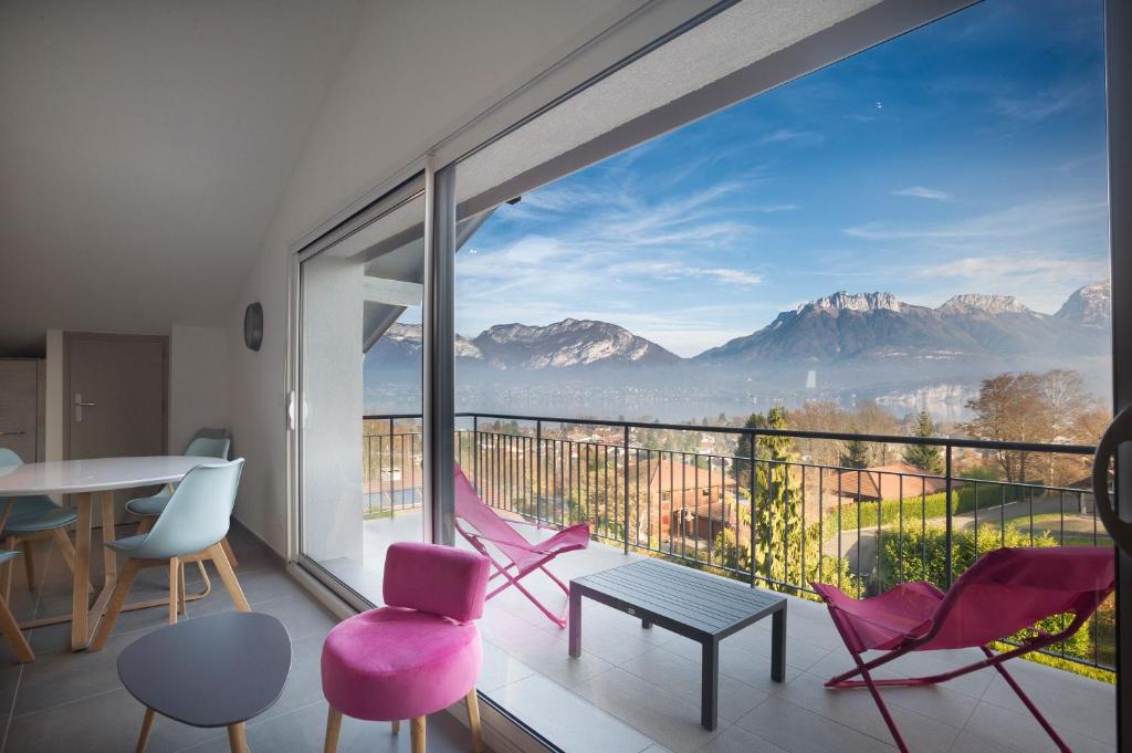 a room with a balcony with a view of mountains at Appartement Mont Blanc - Vue Lac in Sévrier