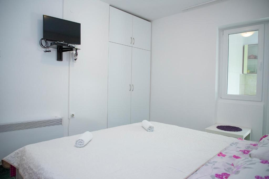 a white bedroom with a bed and a window at 4 Studios Becic in Budva
