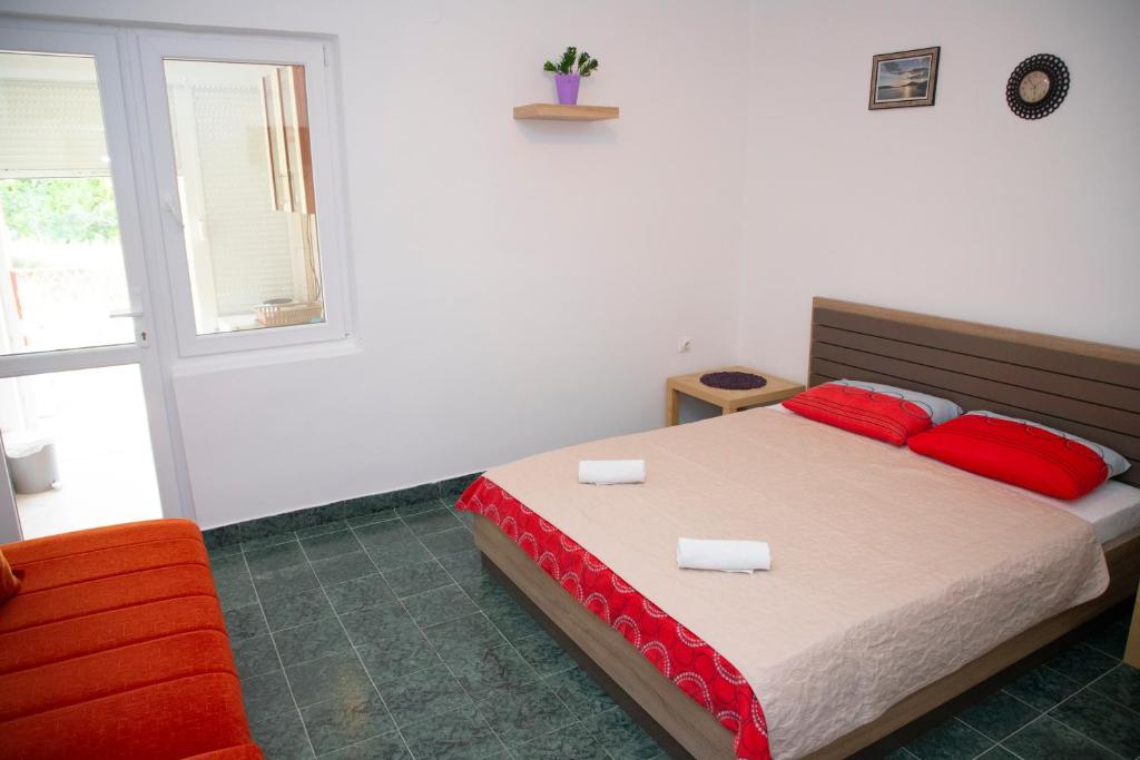 a bedroom with a bed with red pillows and a window at 4 Studios Becic in Budva
