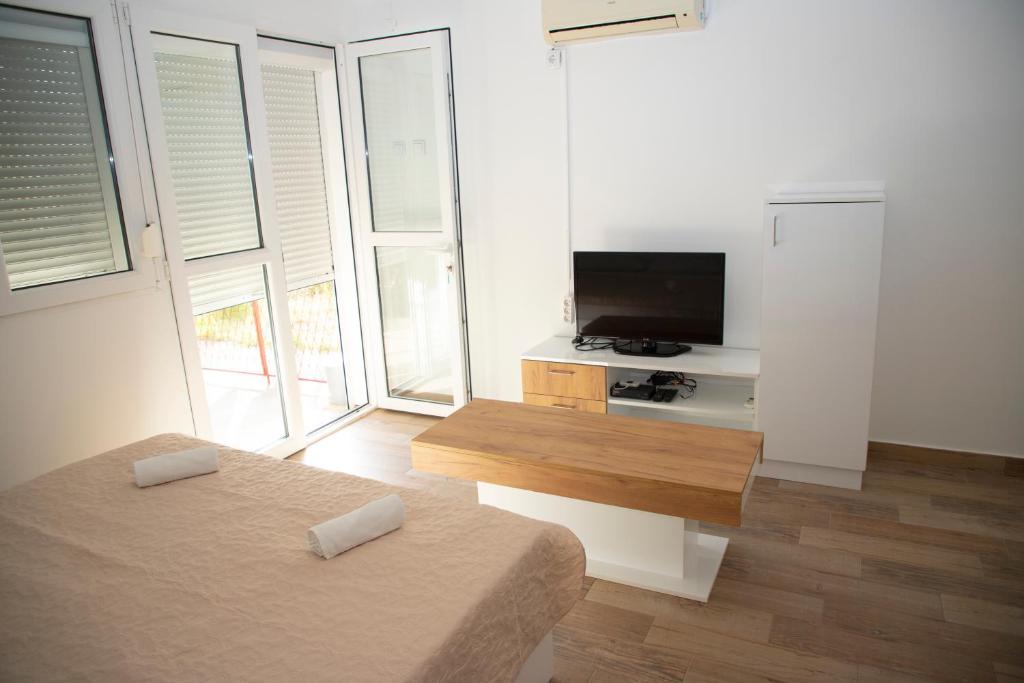 a white living room with a tv and a couch at 4 Studios Becic in Budva