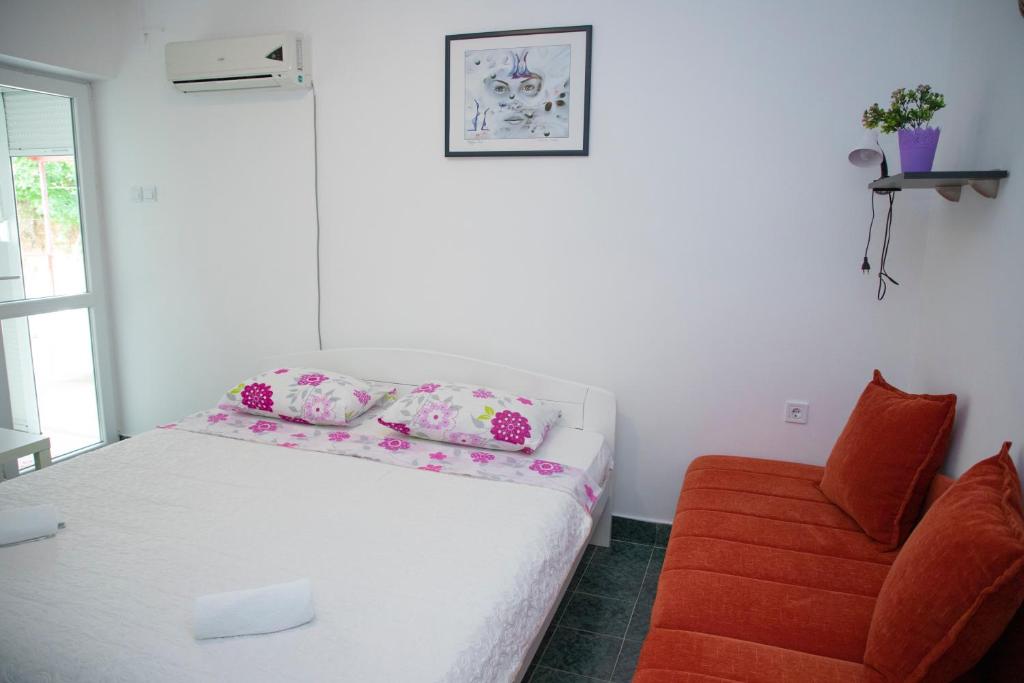 a small bedroom with a bed and a chair at 4 Studios Becic in Budva
