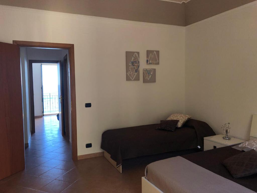 a bedroom with two beds and a door to a balcony at La Casa Sulla Scogliera in Cefalù