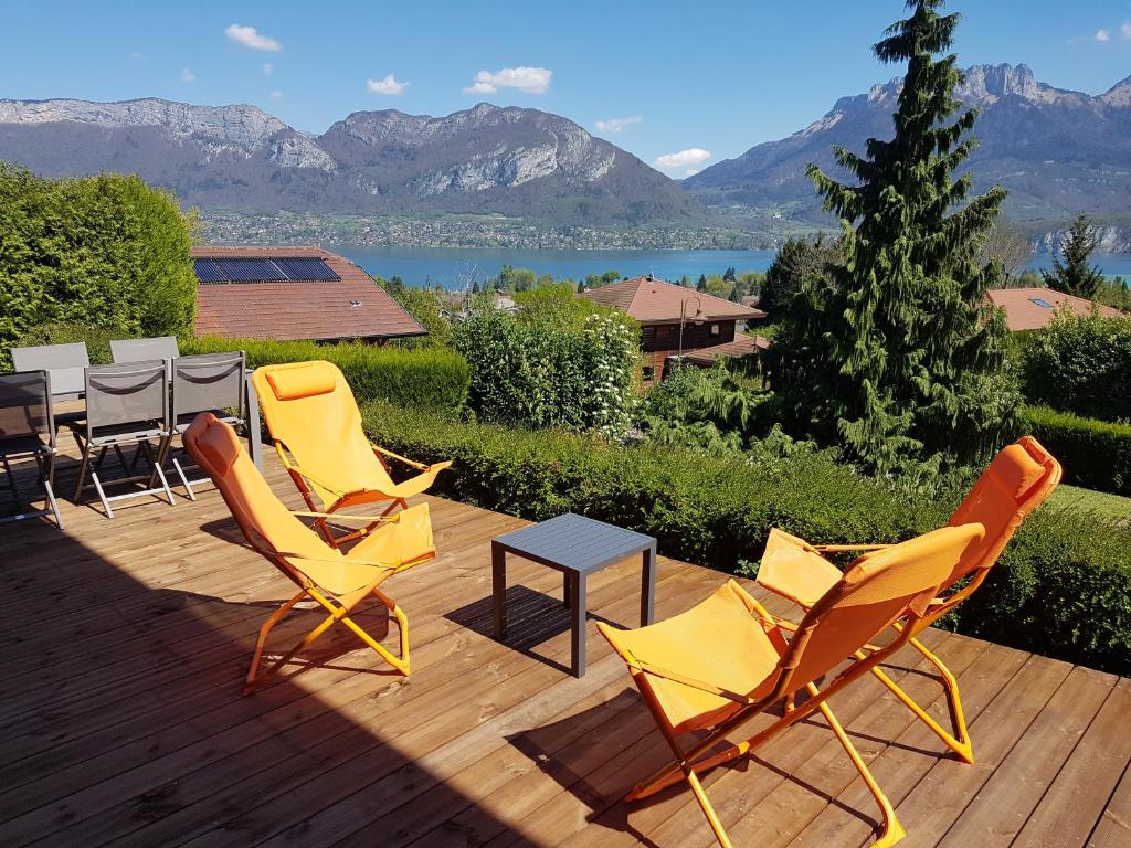 un groupe de chaises et une table sur une terrasse en bois dans l'établissement Appartement Semnoz - Vue Lac, à Sévrier