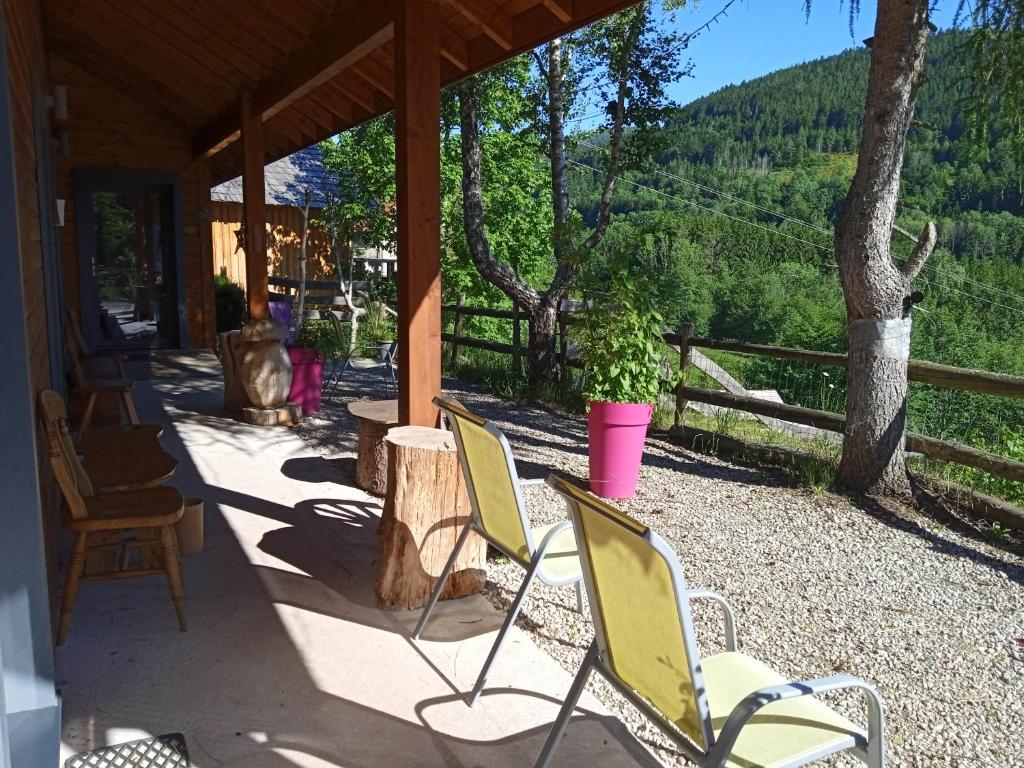 a porch of a house with chairs and a tree at Auberge De La Grange spa & sauna in Plainfaing