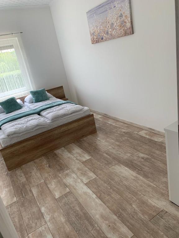 a bedroom with a bed and a wooden floor at BB Vendégház in Villány