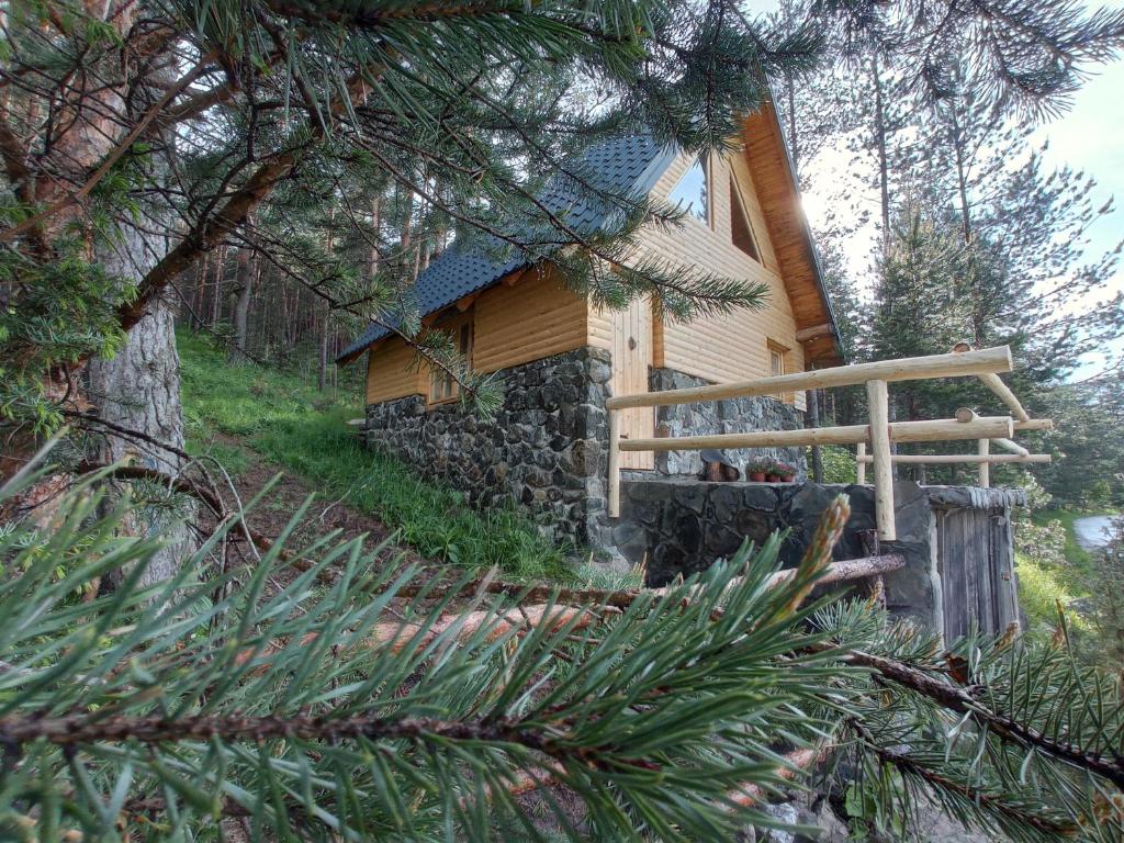 une cabane en rondins dans les bois à côté d'un arbre dans l'établissement Garac Zlatibor Vikendica, à Zlatibor