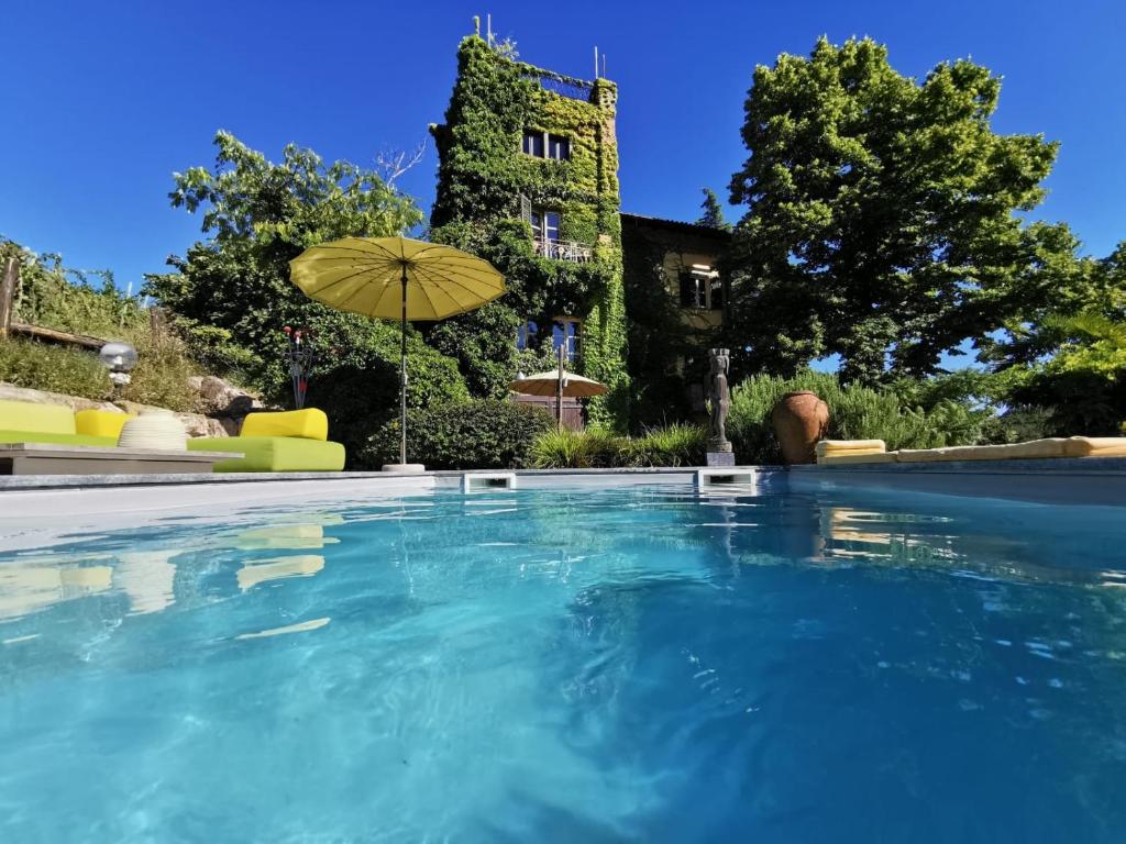 a swimming pool in front of a house with an umbrella at B&B Casa Percivalle in Borgo Priolo