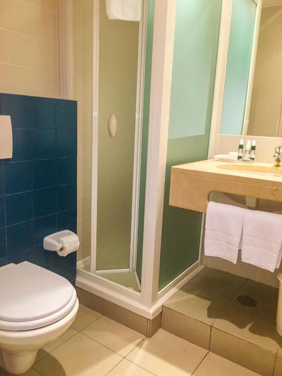 a bathroom with a shower and a toilet and a sink at Marina Club Lagos Resort in Lagos