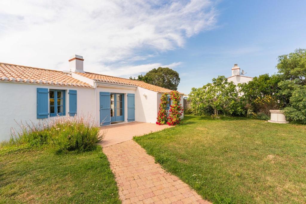 une maison blanche avec des portes bleues et une cour dans l'établissement Maison tout confort en front de plage a Noirmoutier en l ile, à Noirmoutier-en-l'lle