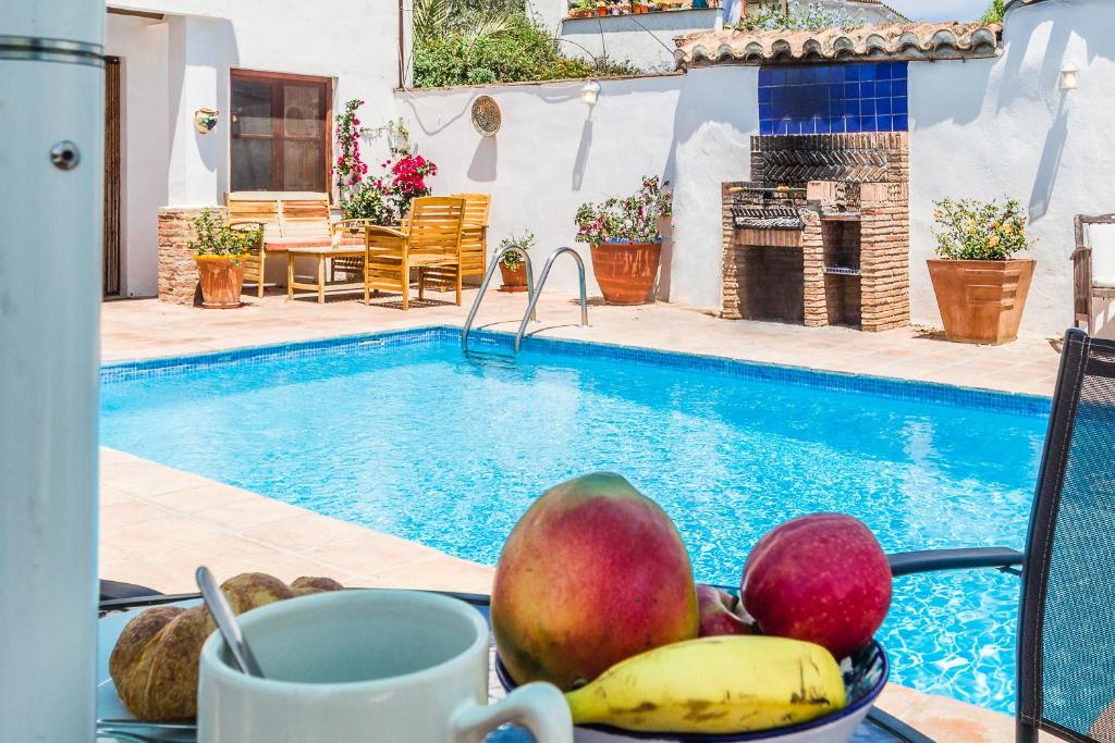 a plate of fruit next to a swimming pool at Casa Luna - 16th century traditional spanish village house in Pinos del Valle