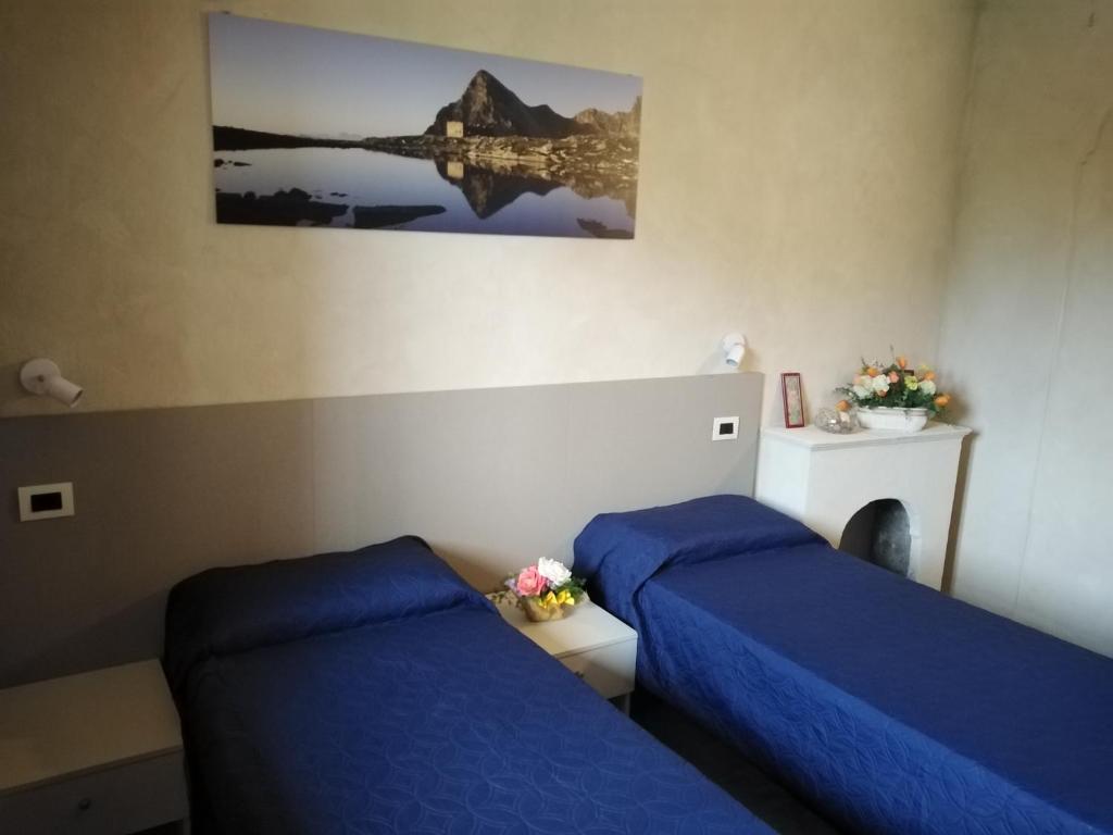 Ostello del Monastero في درونيرو: سريرين في غرفة ذات أغطية زرقاء