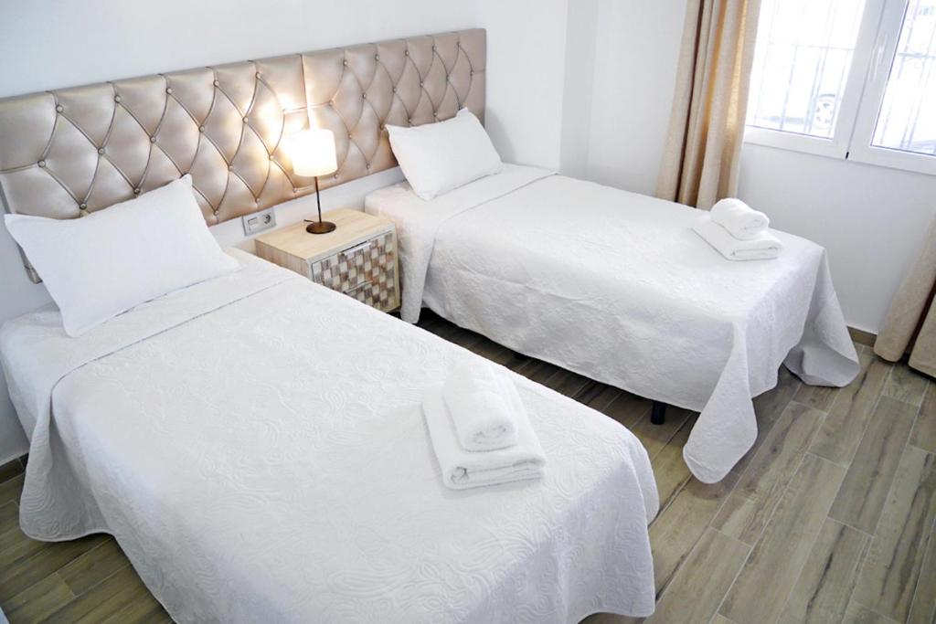 pokój hotelowy z dwoma łóżkami z białymi prześcieradłami w obiekcie Neenies Nerja - Carabeo Luxury Apartment w mieście Nerja