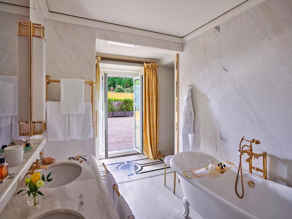 a white bathroom with a tub and a sink at Hotel Eden - Dorchester Collection in Rome