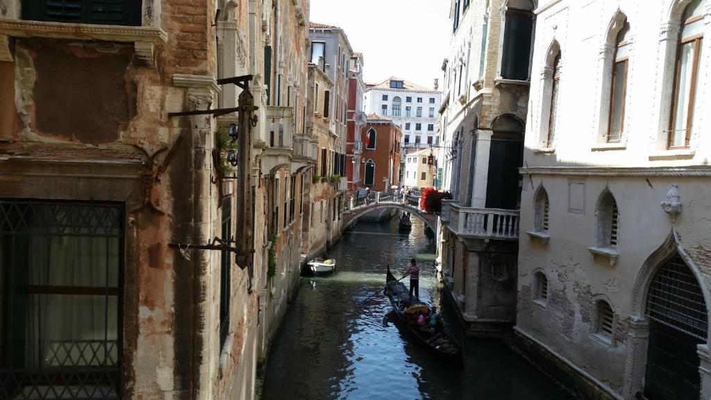 a canal between two buildings with a bridge and a boat at Palazzo Eugenia - Minelli in Venice
