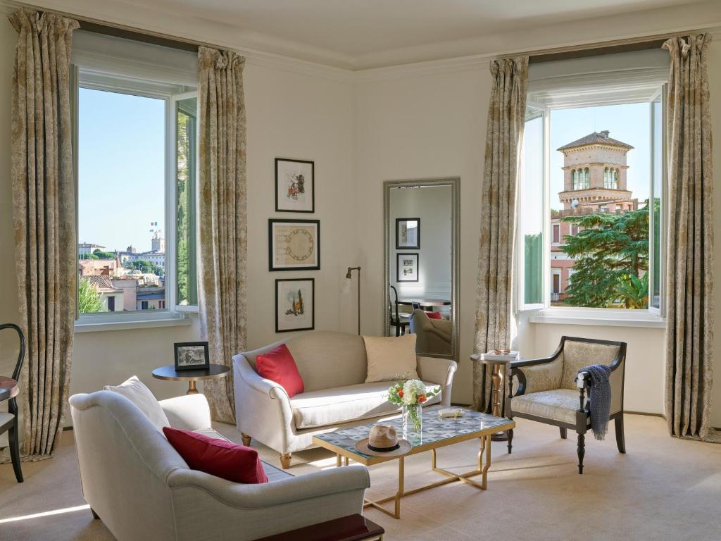 a living room with a couch and chairs and windows at Hotel Eden - Dorchester Collection in Rome