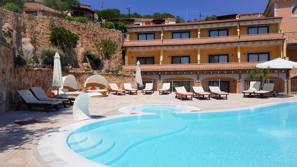 a hotel with a swimming pool with chairs and umbrellas at Hotel Pozzo Sacro in Olbia