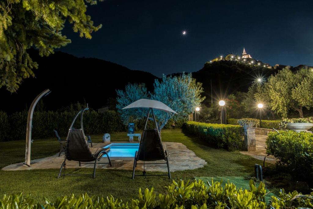 dwa krzesła i parasol przy basenie w nocy w obiekcie Il Riparo w mieście Guardialfiera