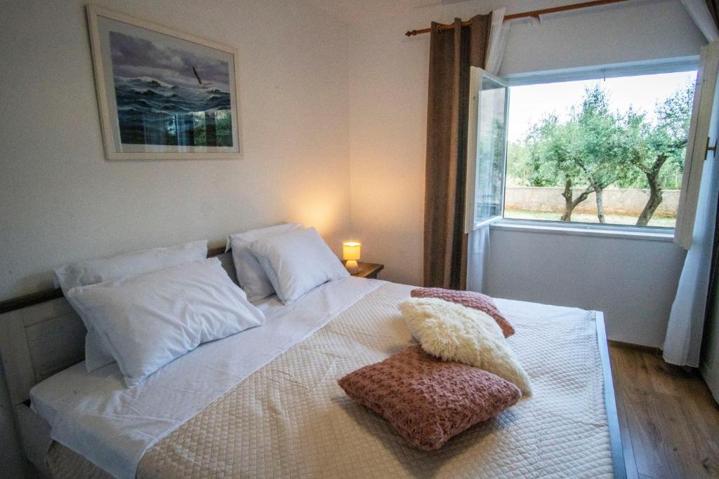 a bedroom with a white bed with a window at House Nada apartman in Muntić