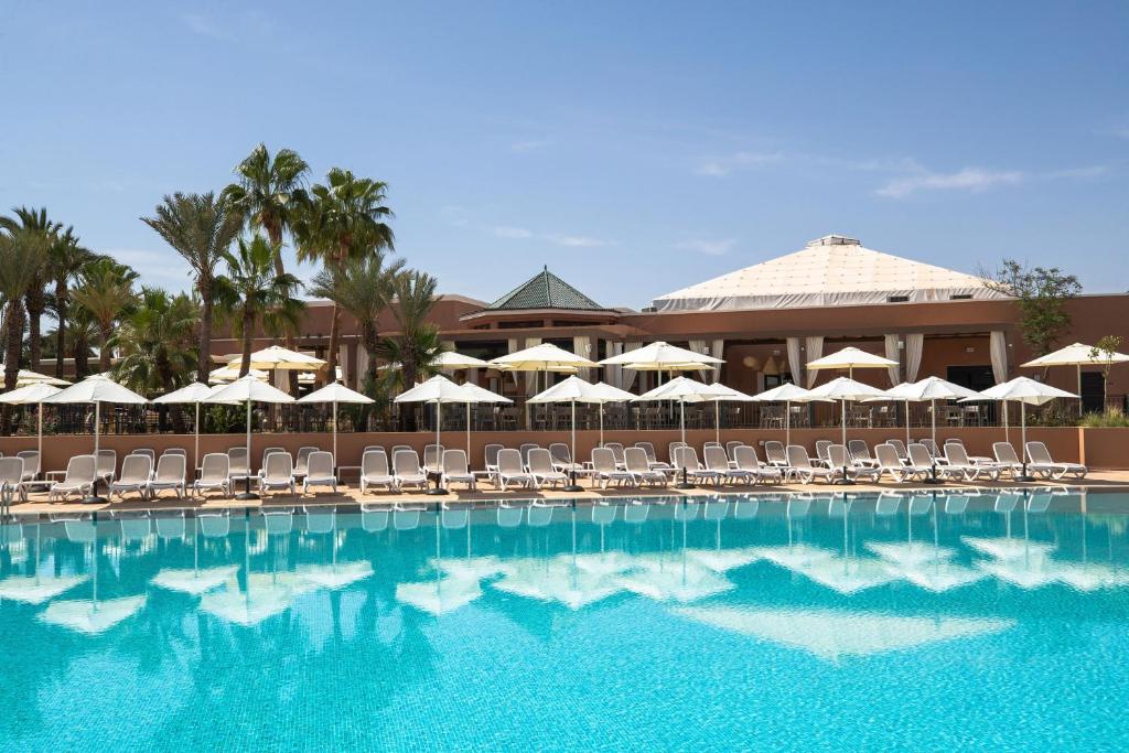 a large swimming pool with chairs and umbrellas at Sol Oasis Marrakech - All Inclusive in Marrakesh