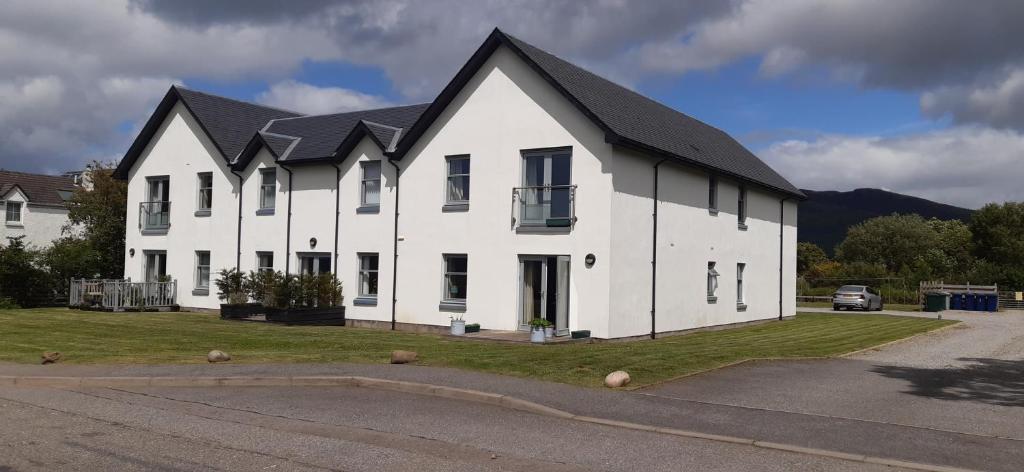 a white house with a black roof at One The Cairns in Connel