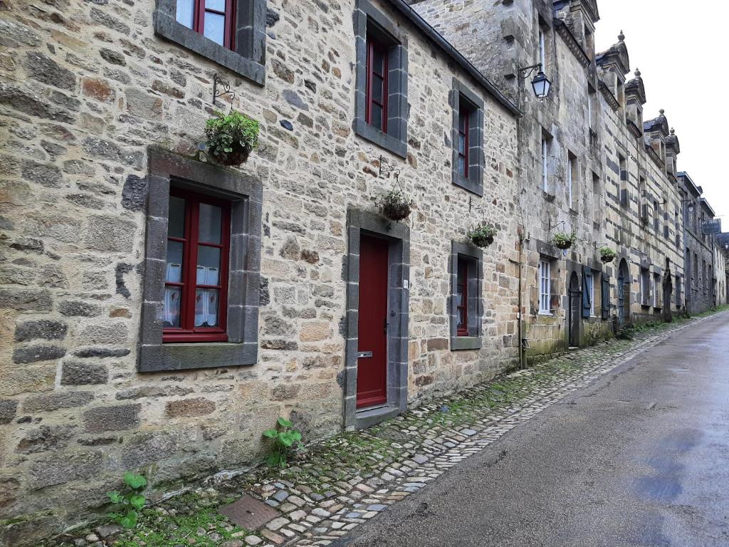 ein altes Steingebäude mit roten Türen und Fenstern in der Unterkunft TY KOANT in Daoulas