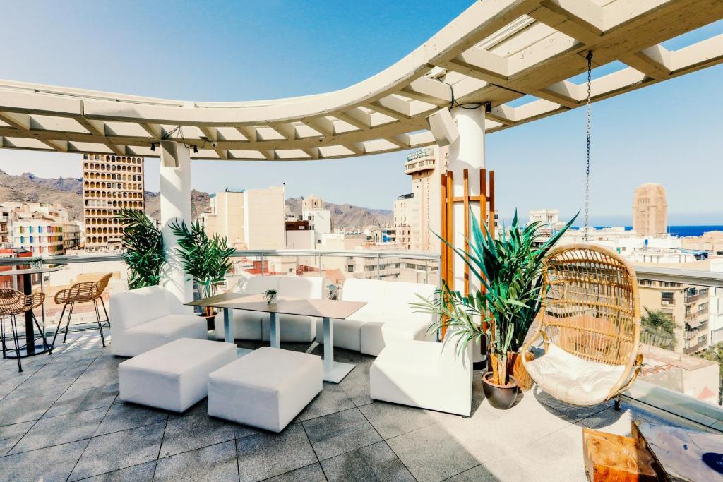 a rooftop patio with white furniture and a view of the city at Urban Anaga Hotel in Santa Cruz de Tenerife