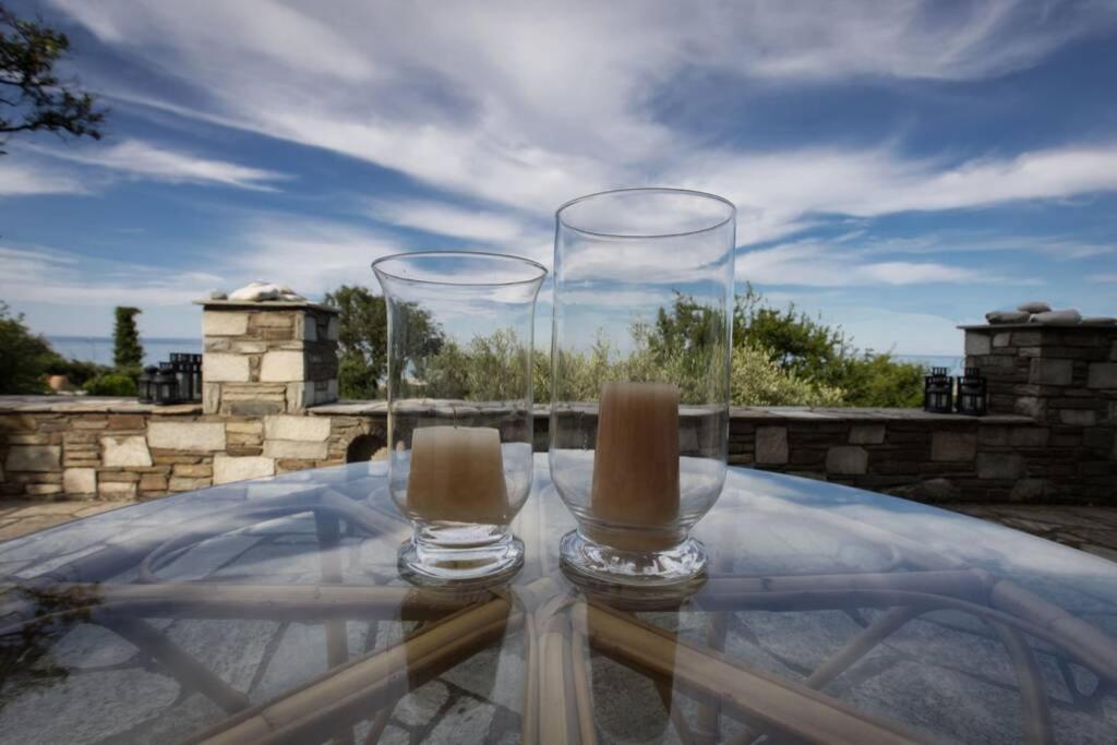 dwa puste szklanki siedzące na szklanym stole w obiekcie Aegean's Whispery Seafront Villa w mieście Chorefto