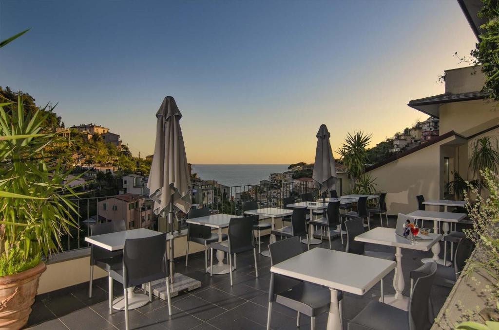 リオマッジョーレにあるホテル ヴィラ アルジェンティーナのテーブルと傘と海を備えたレストランを併設しています。