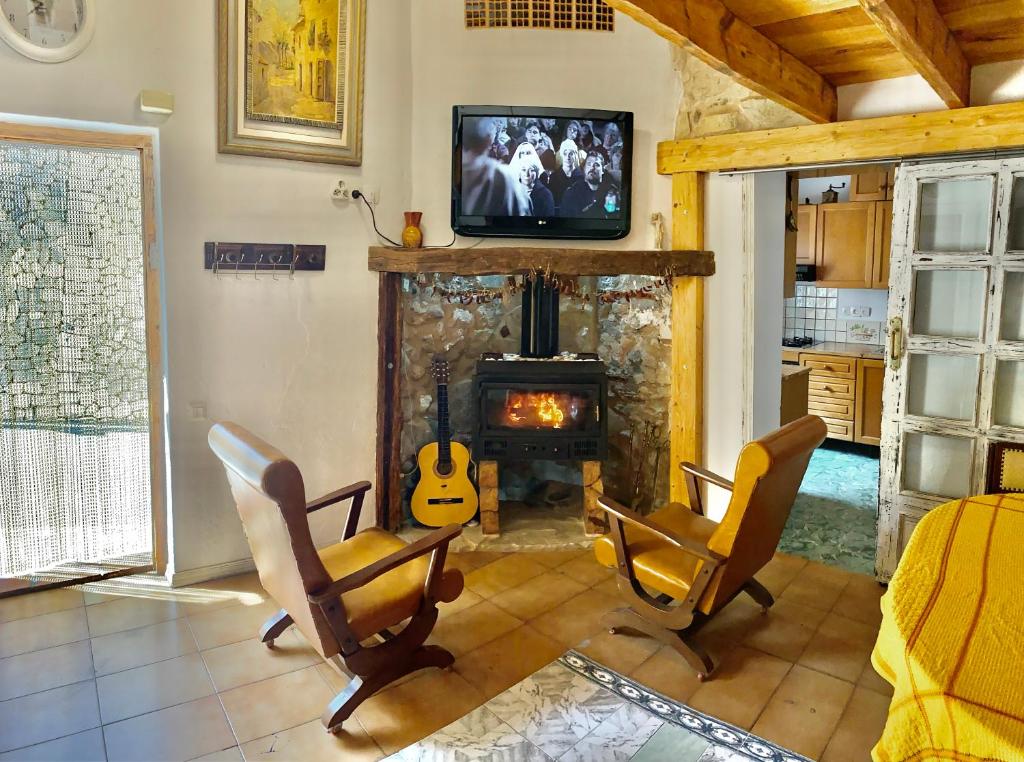 a living room with a fireplace with two chairs and a television at Altea Old Town Cottage in Altea