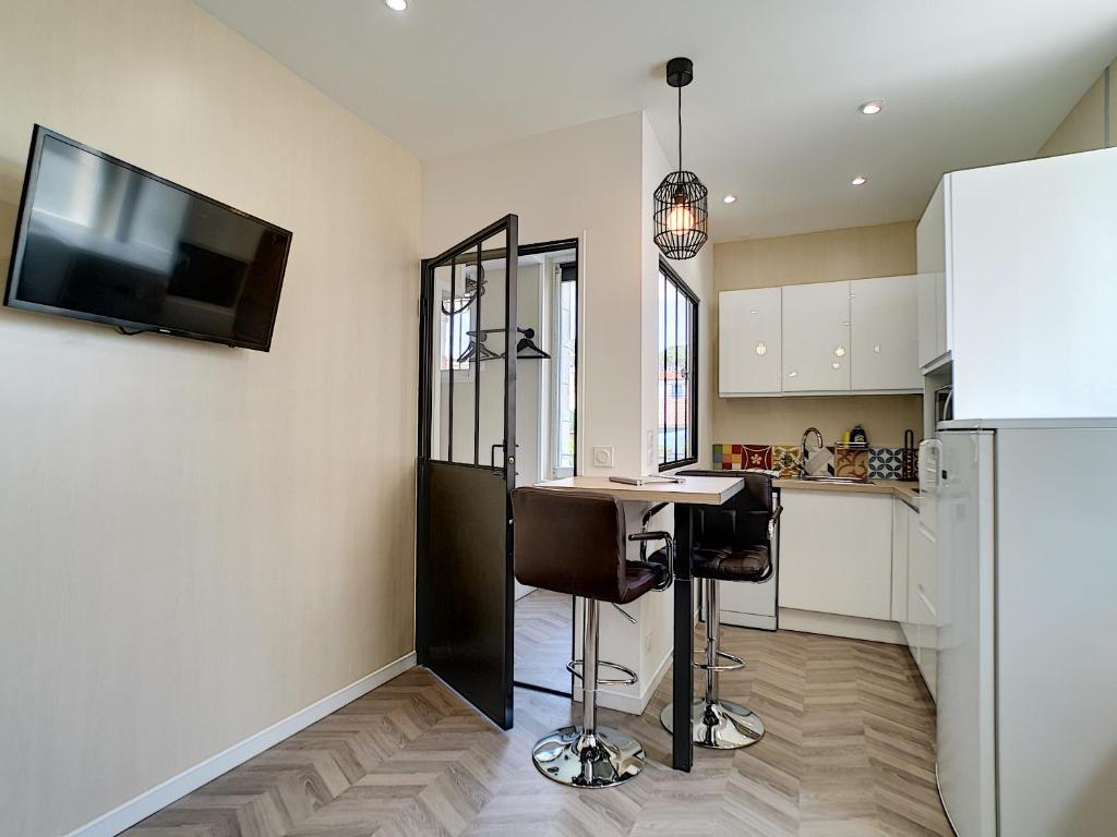 ロワイヤンにあるHermès Plageのバースツールと壁掛けテレビのあるキッチン