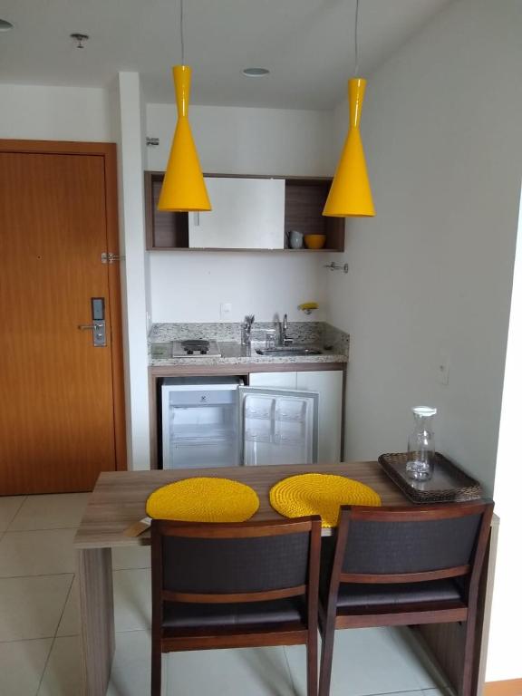 a kitchen with a wooden table and yellow cushioned chairs at Acomodação Tranquila (Centro de Campos) in Campos dos Goytacazes