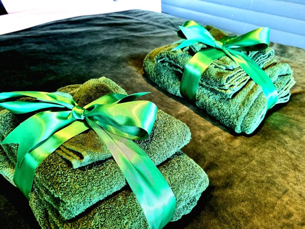 two towels with green bows on top of a bed at Yaseva Lodge, Stylish Country Retreat for 2, Hot Tub, Exceptional Views! in Carr