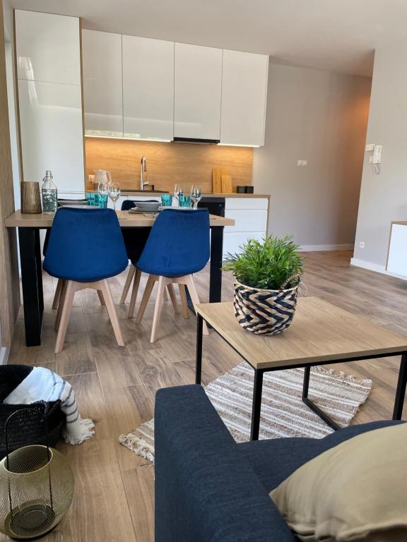 a kitchen with a table and blue chairs in a room at Apartament Marble Wave Rowy in Rowy
