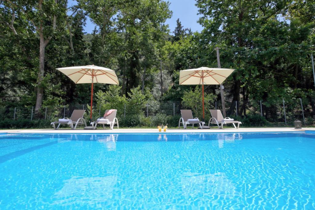 a swimming pool with two umbrellas and two chairs at Villa Ligero in Palaiokatoúna