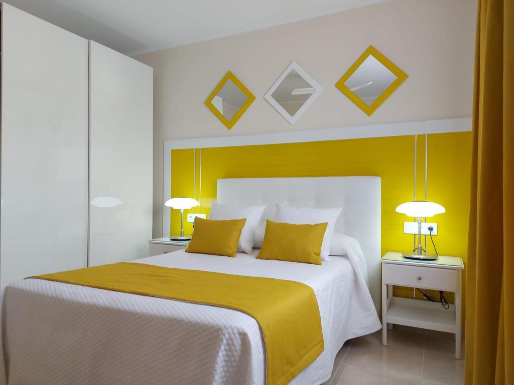 una camera con un letto con testata gialla e due lampade di El Hierro a Gran Tarajal