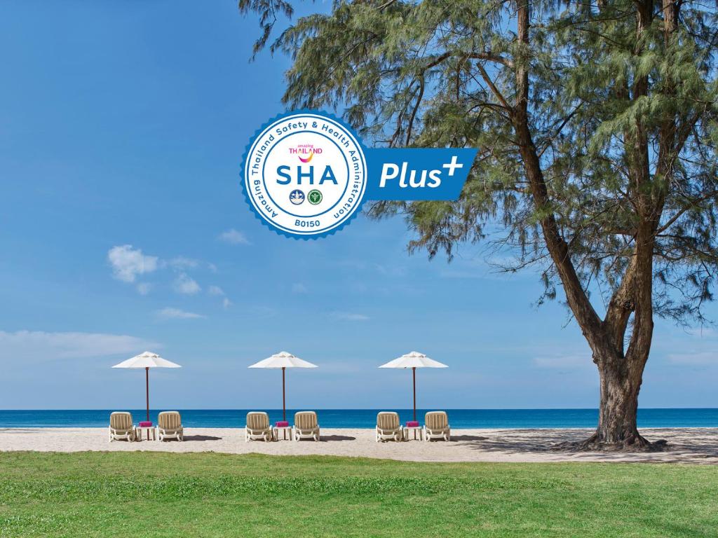 a beach with a beach chair and some palm trees at Dusit Thani Laguna Phuket - SHA Extra Plus in Bang Tao Beach