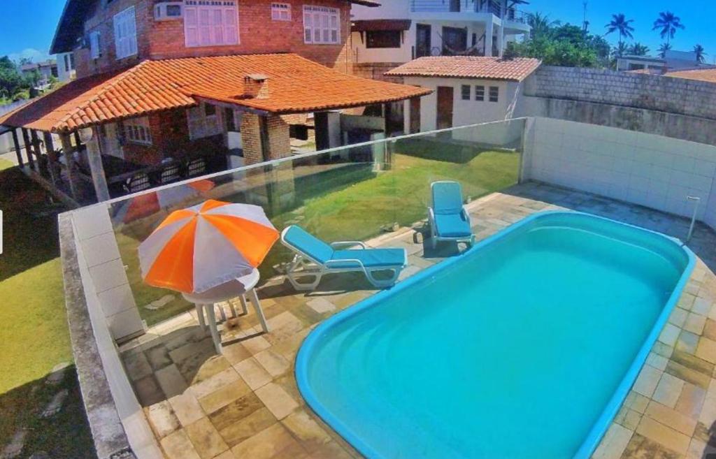 een zwembad met een parasol en twee stoelen en een parasol bij Casa Laser praia Cumbuco in Cumbuco
