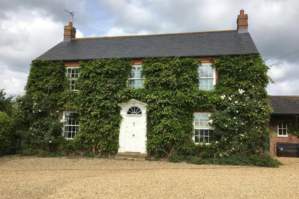 Private Annex near Melton Mowbray في ميلتون موبراي: منزل مغطى ivy مع باب أبيض
