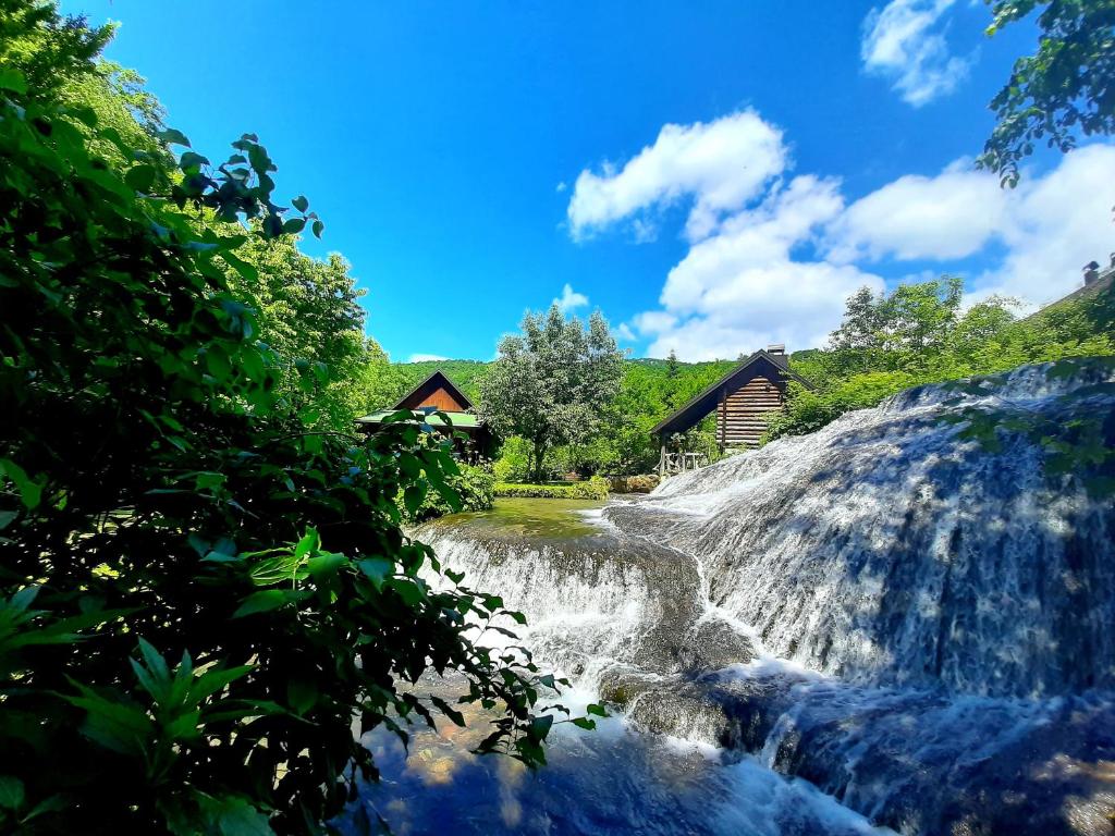 a waterfall in front of a log cabin at Janjske otoke - smještaj na selu (Milorad Piljić) in Šipovo