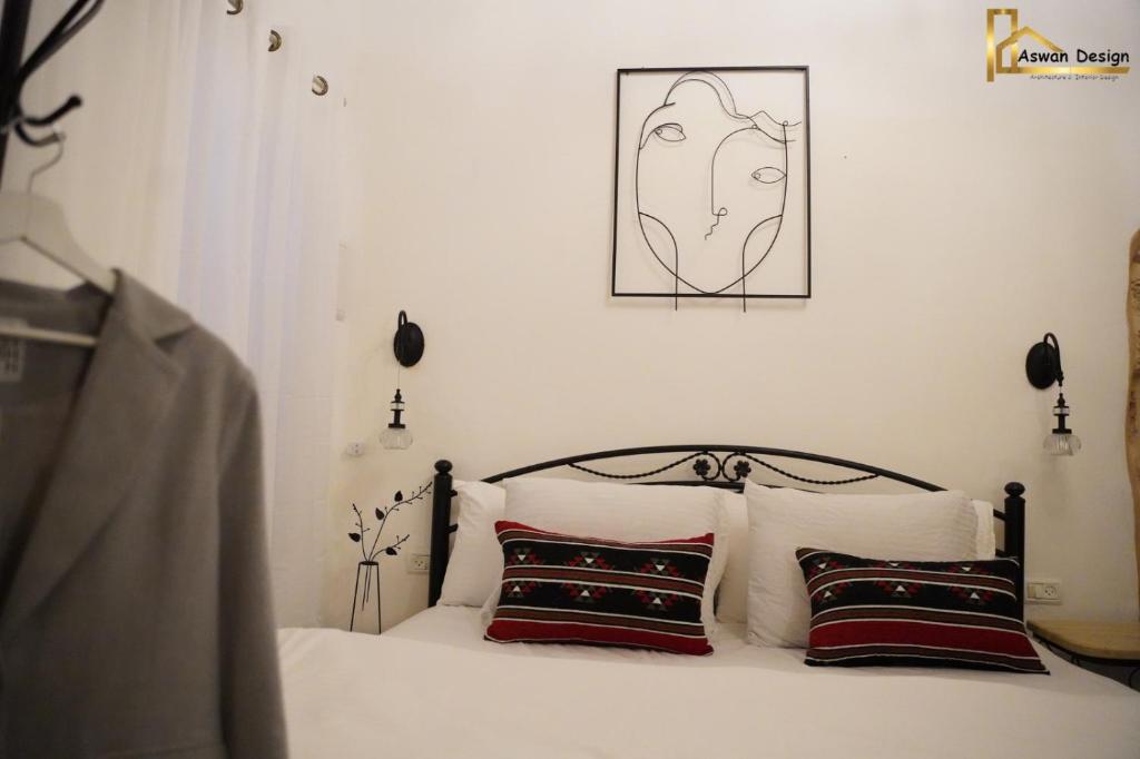 a bed with two pillows and a picture on the wall at تاج عكا Taj Akko in ‘Akko