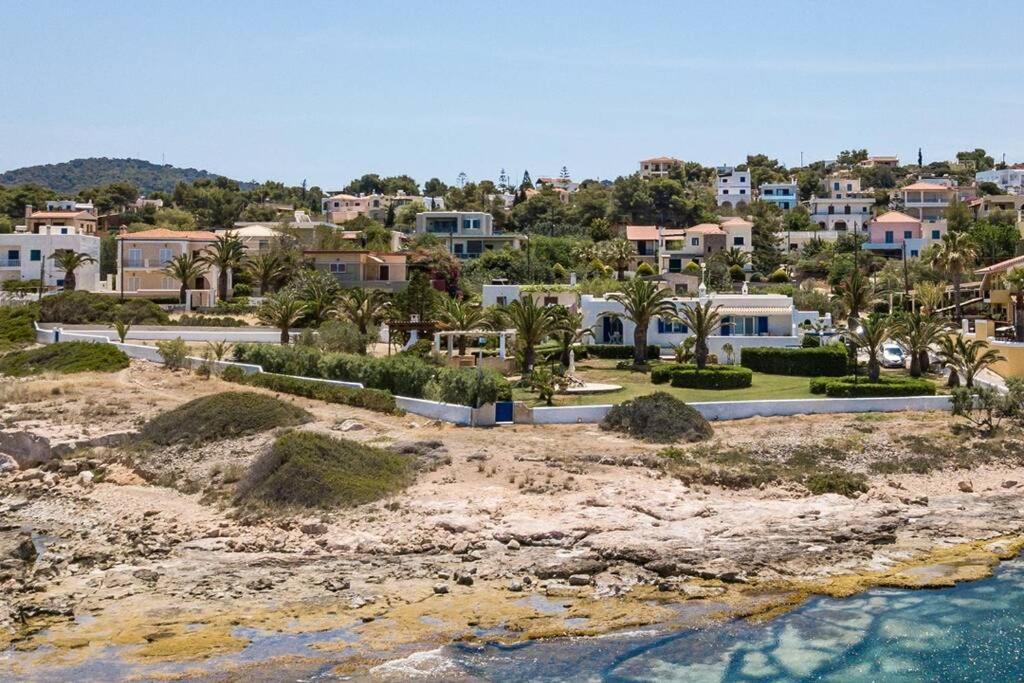 a group of houses on a beach next to the water at Palmaya Villa, unique seafront experience in Vaia