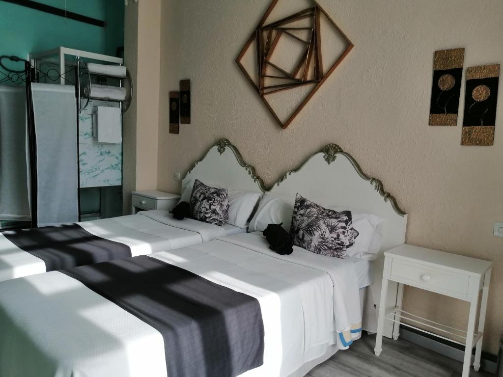 a bedroom with two beds with white sheets and a mirror at Hospedaje Botin in Santander