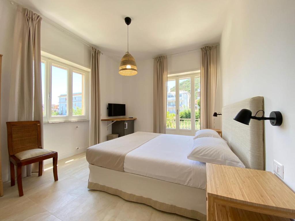 a bedroom with a bed and a chair and windows at Maison Sciscì Rooms in San Felice Circeo