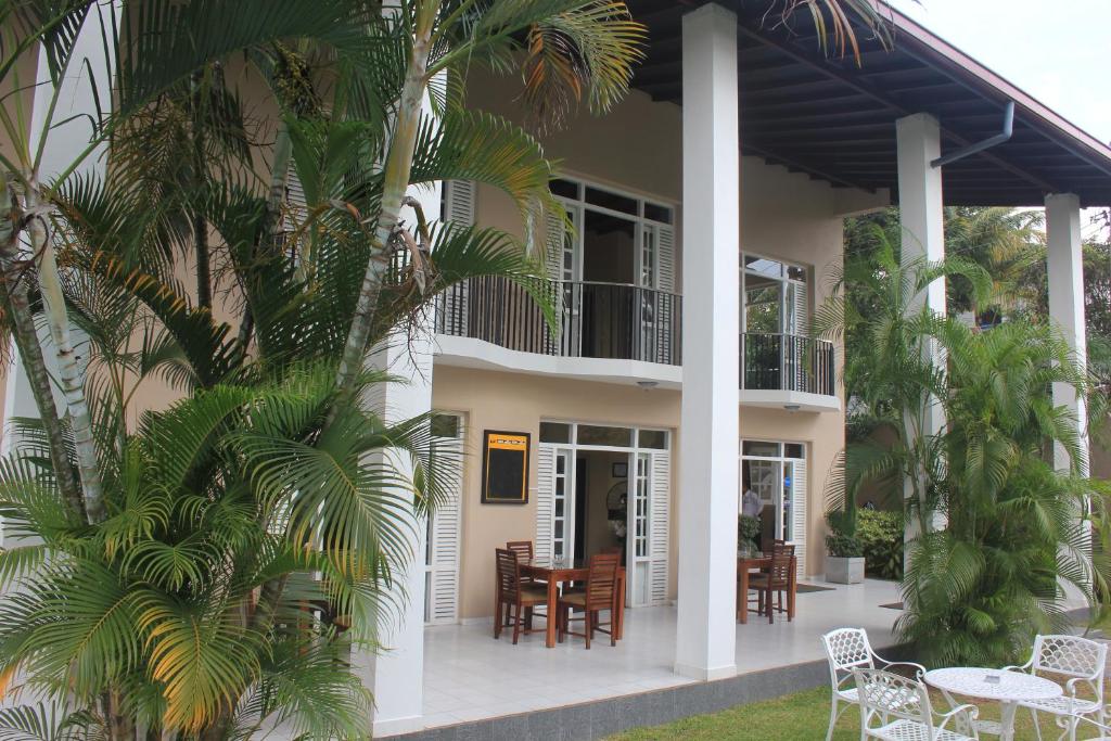 una casa con mesa, sillas y palmeras en Grand 7 Hotel Thalawathugoda, en Talawatugoda