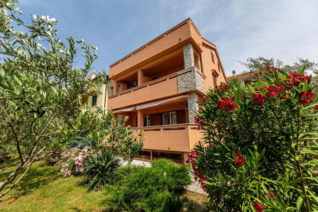 a building with red flowers in front of it at Apartments Creska in Baška