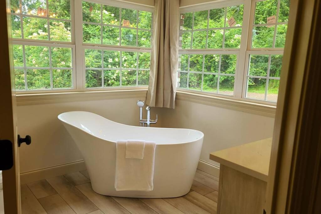 baño con bañera blanca y ventanas en Farm House stay with soaking tub and hot tub barn en Hammond